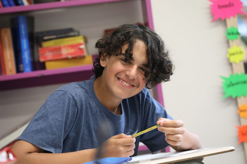 A smiling high school student in a classroom at Oakwood Friends School