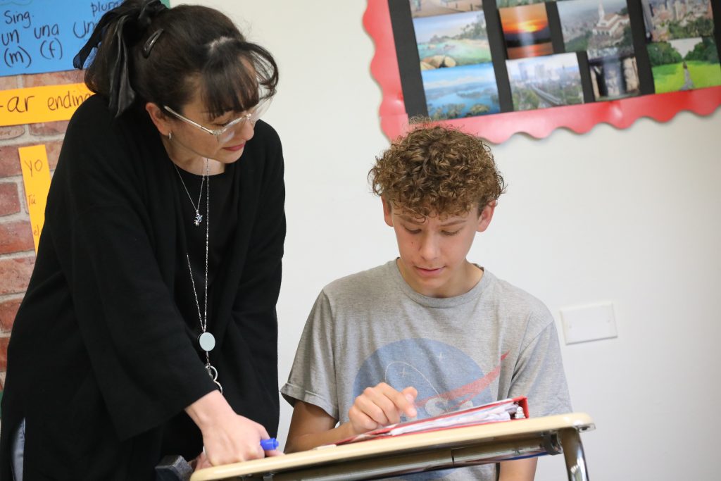 A teacher guides a student through his classwork